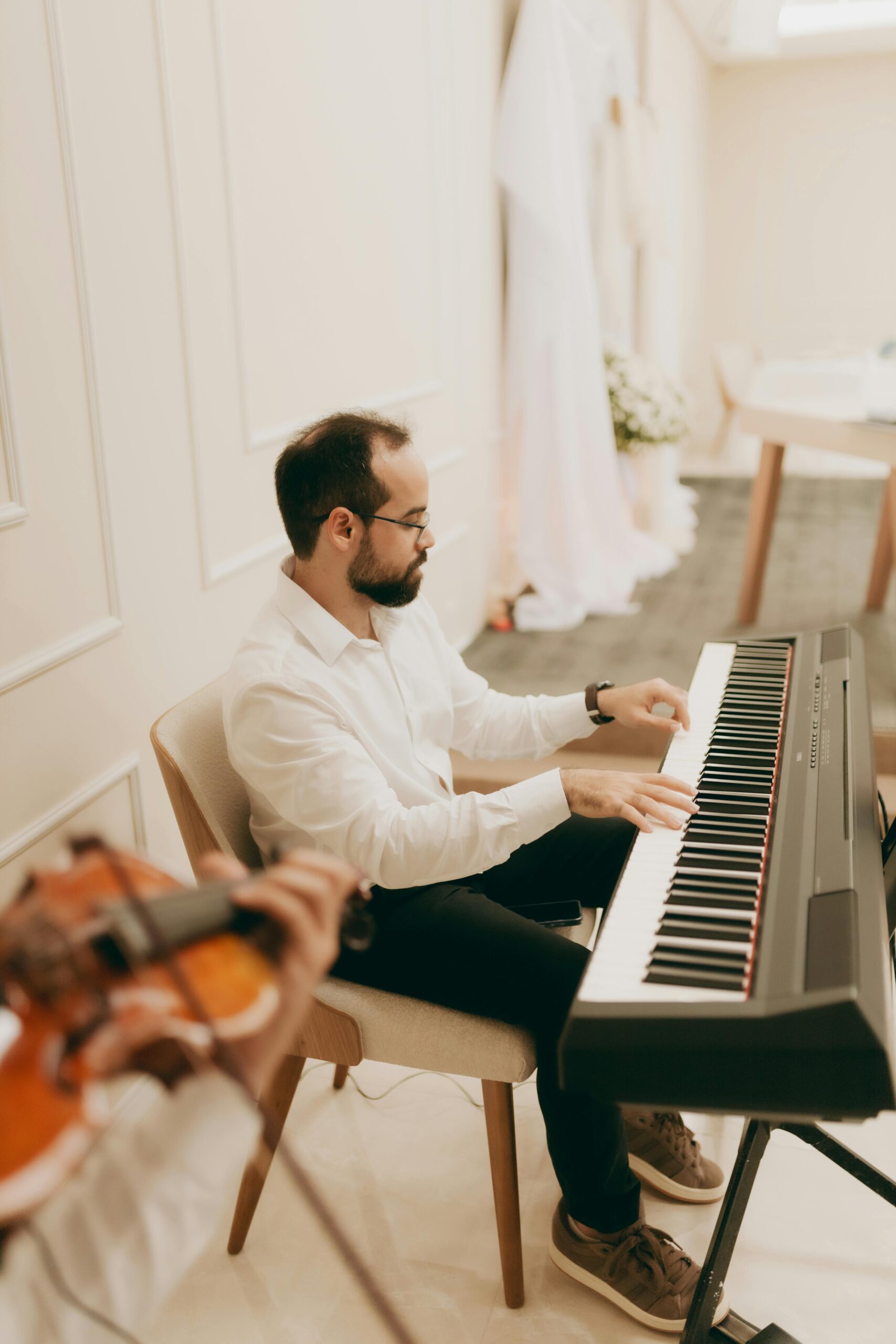 Man plays keyboard piano in a sophisticated indoor setting, creating a harmonious atmosphere.
